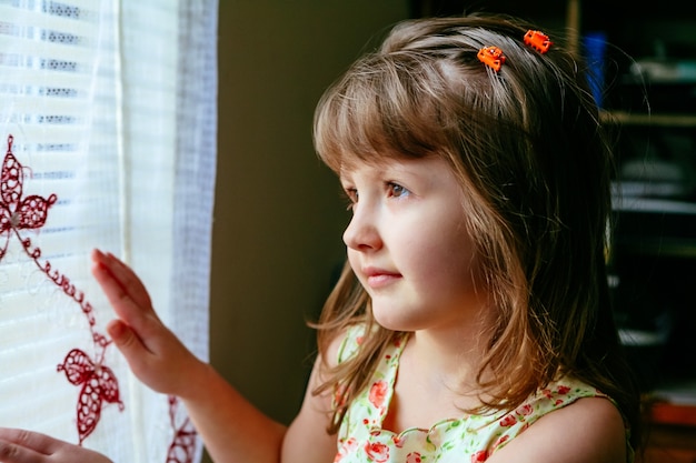 Niña triste mirando la ventana