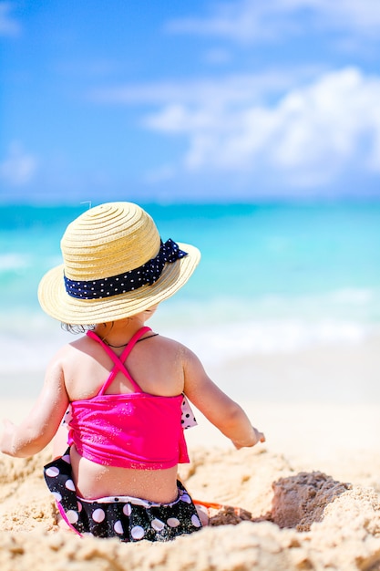 Niña en tropical playa blanca haciendo castillos de arena