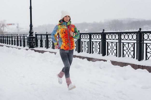 Una niña trota en un día helado y nevado. Deportes, estilo de vida saludable.