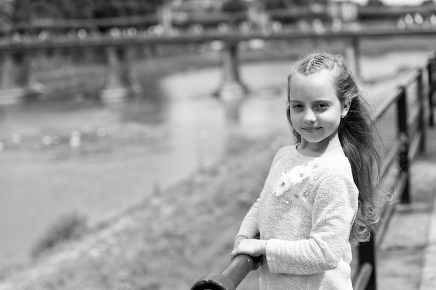 Niña turista disfruta de hacer turismo mientras camina Niño niña con cabello largo camina cerca del río junto al río en el fondo Niña o colegiala de vacaciones disfruta de viajar y hacer turismo Concepto de vacaciones