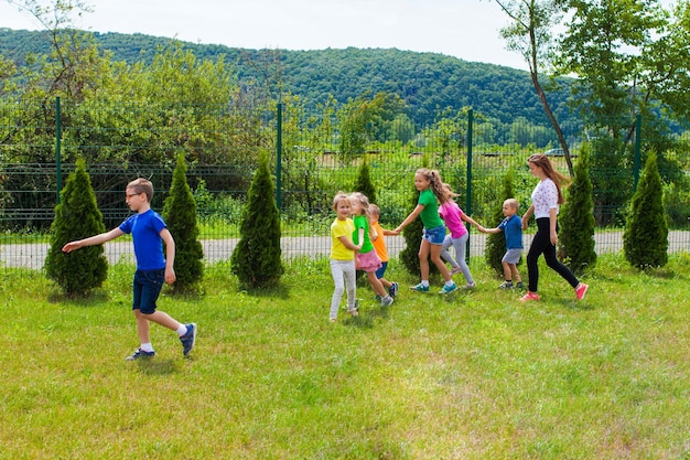 Niña tutora camina con niños. Campamento de verano para compañeros de colegio