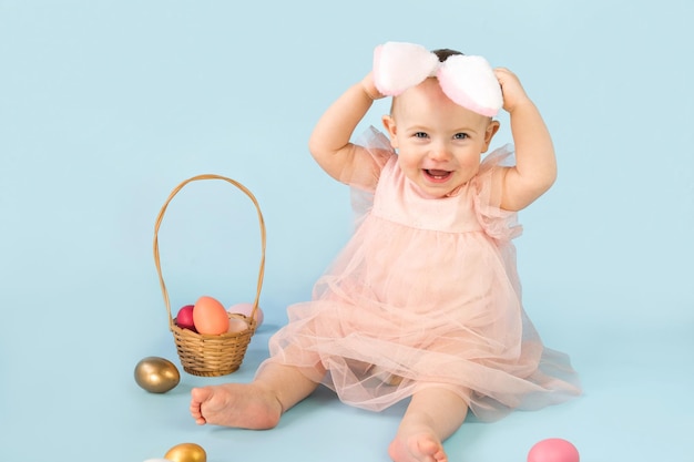 Una niña con un tutú rosa se sienta frente a una canasta de huevos de Pascua.