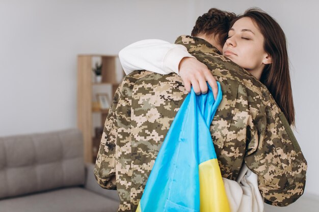 Una niña ucraniana abraza y sostiene una bandera amarilla y azul de un militar uniformado y se despide de él