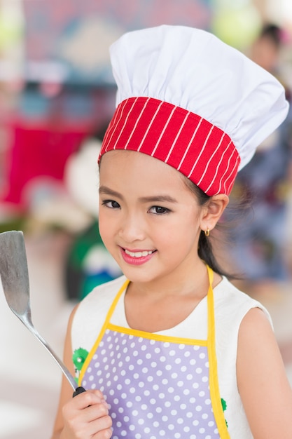 Foto niña en uniforme de cocinero con cucharón