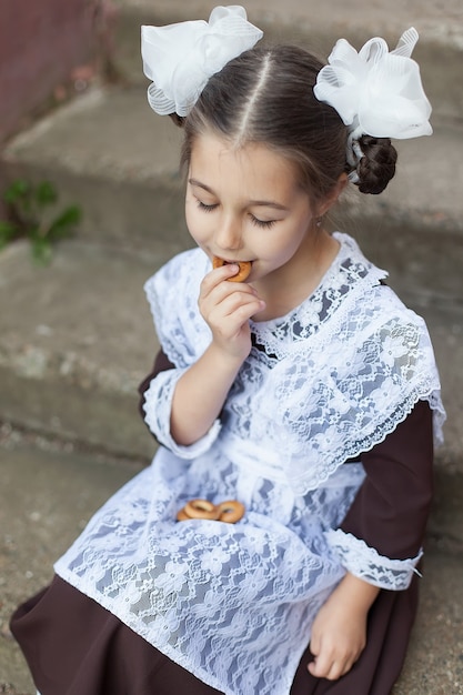 Una niña en uniforme escolar comiendo bocadillos.