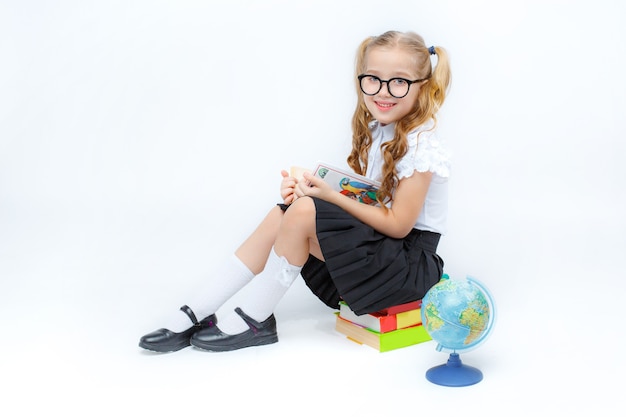 Niña en uniforme escolar con gafas aislado sobre un fondo blanco.