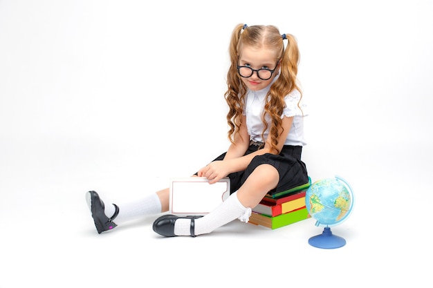 Niña en uniforme escolar con gafas aislado sobre un fondo blanco.