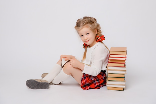 Niña en uniforme escolar con un libro en sus manos sentado