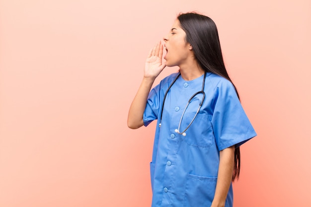 Niña con uniforme médico y estetoscopio gritando ruidosamente con la mano al lado de la boca