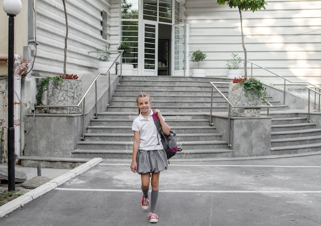 Niña en uniforme a pie de la construcción de la escuela.