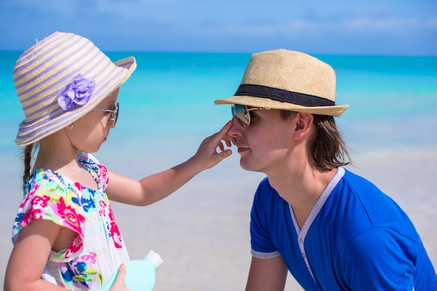 Niña untando la nariz de su padre Crema de protección solar