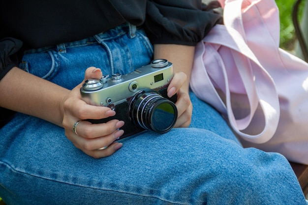 una niña usa una cámara, una cámara en las manos, un hombre en el parque, pasatiempos, fotoperiodismo, una niña toma una foto