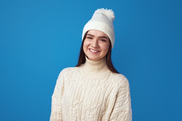La niña usa gorro y un suéter de punto de gran tamaño se siente alegre disfrutar del invierno