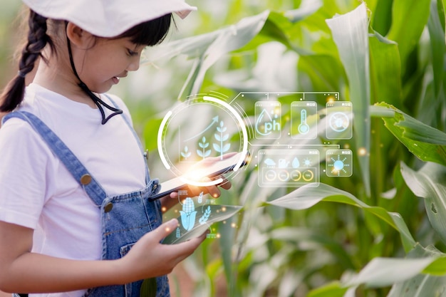 La niña usa una tableta para analizar el crecimiento de las plantas en la parcela agrícola y el ícono visual el concepto de tecnología agrícola Concepto de aprendizaje de agricultura inteligente