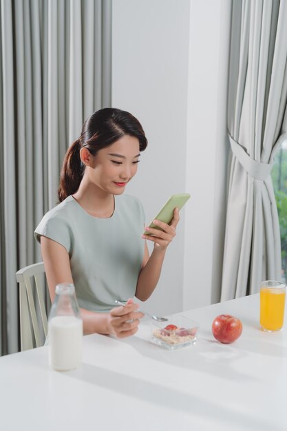 La niña usa el teléfono durante el desayuno.