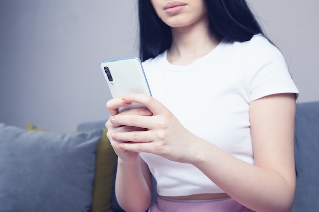 Niña usa el teléfono mientras está sentada en el sofá