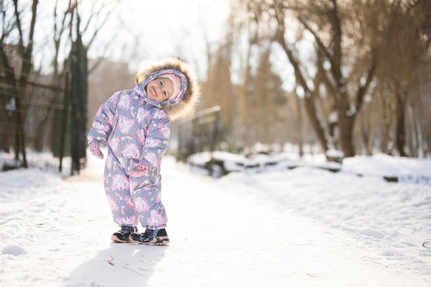 La niña usa traje de nieve para niños en un día soleado de invierno helado