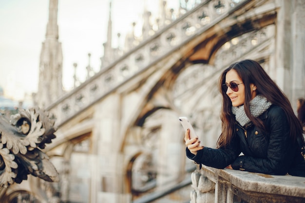 niña usando su teléfono mientras explora el duomo en Milán Italia