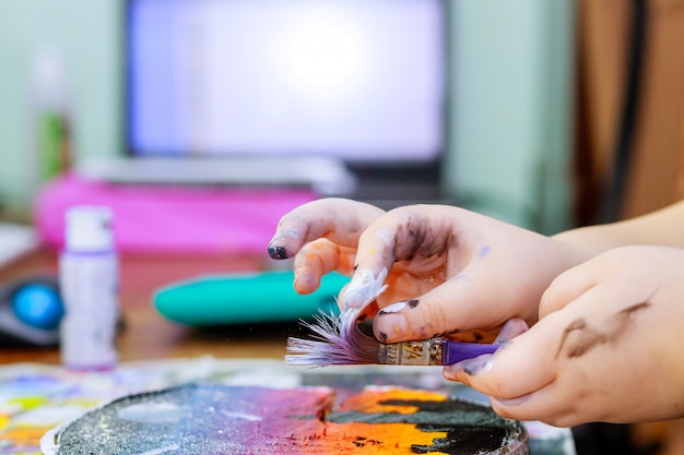 Foto niña utiliza pinceles de pinturas de colores una imagen en madera