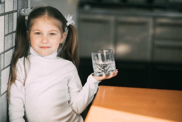 niña con un vaso de agua en sus manos muy dulce