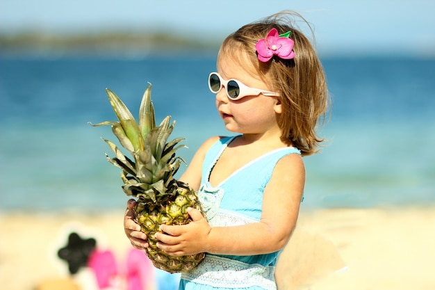 Niña en vasos con piña cerca del verano del mar