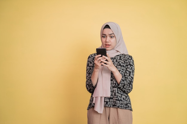 Una niña con velo se sorprende al ver la pantalla de un teléfono móvil con copyspace