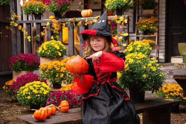 niña vestida de bruja con calabaza celebra halloween