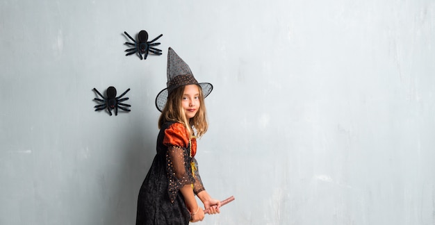 Niña vestida de bruja para las vacaciones de halloween arriba en la escoba y volando