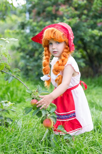 Niña vestida de Caperucita Roja en el jardín