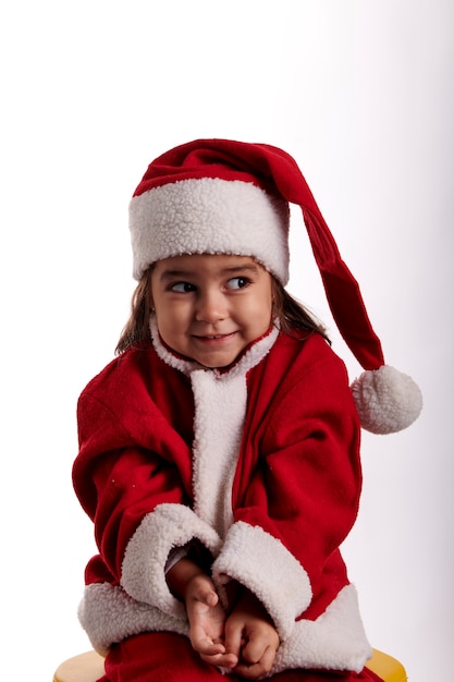 Una niña vestida como Santa Claus y mirando hacia un lado.