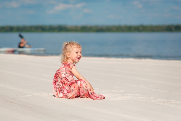 Una niña vestida con una hermosa Sarafna juega en la arena de la playa.