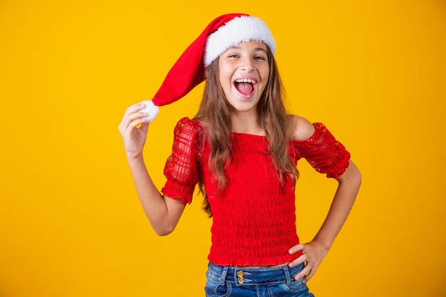 Niña vestida para Navidad encantada sosteniendo el pompón del sombrero