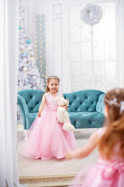 Niña vestida con osito con sofá y árbol de Navidad