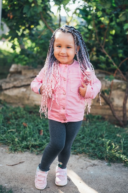 Foto una niña vestida de rosa con coletas afro rosadas.