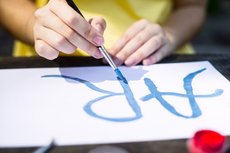Foto una niña en un vestido amarillo escribe pinturas en una hoja de papel la palabra arte