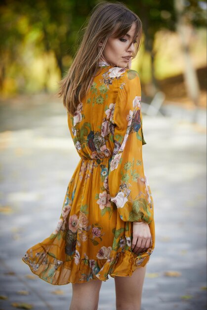 Una niña con un vestido amarillo con el telón de fondo de un parque de otoño