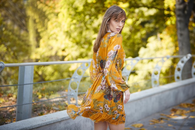 Una niña con un vestido amarillo con el telón de fondo de un parque de otoño