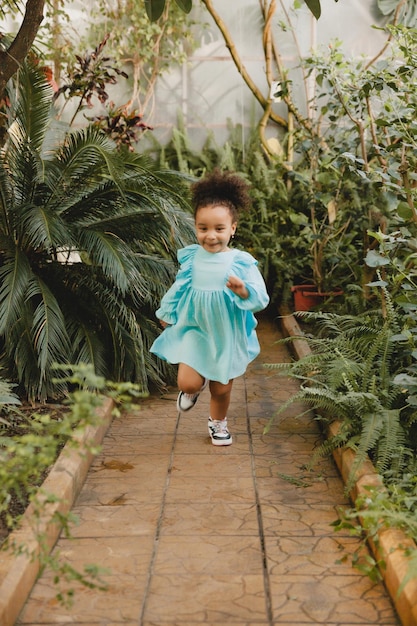 Una niña con un vestido blanco corre por el camino del jardín botánico.