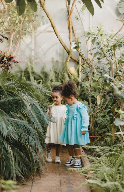 Una niña con un vestido blanco corre por el camino del jardín botánico.