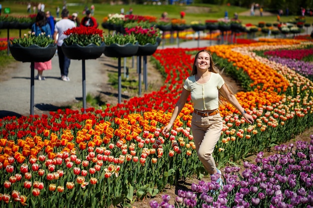 Una niña con un vestido blanco corre entre los tulipanes Campo con tulipanes amarillos y rojos