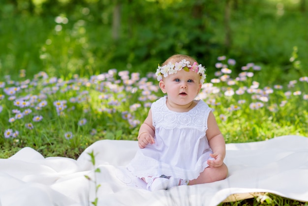 Niña en vestido blanco en un jardín de primavera con flores