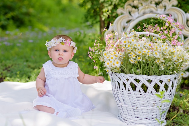 Niña en vestido blanco en un jardín de primavera con flores