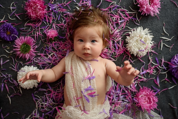 Niña en vestido blanco jugando con ramo de flores