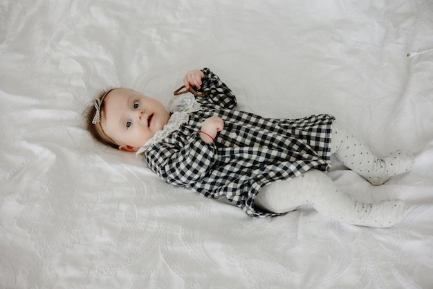 Una niña con un vestido blanco y negro yace en una cama.