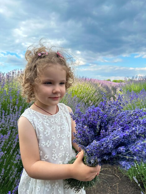 Niña con vestido blanco y ramo de lavanda.