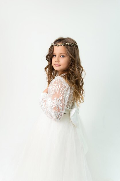 Una niña con un vestido blanco con una tiara en la cabeza posando en el estudio Fondo blanco