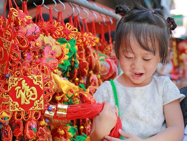 Niña en vestido chino contra decoraciones rojas tradicionales chinos son muy populares