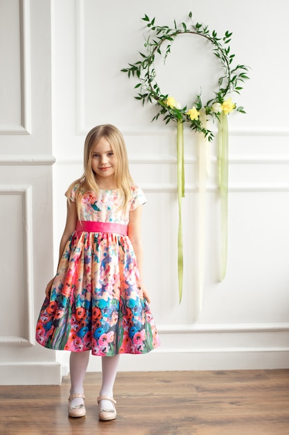 Foto niña en vestido colorido posando interior