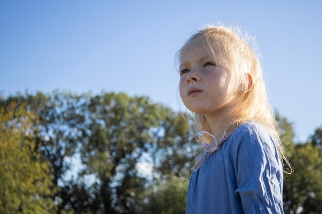 Niña con un vestido contra el cielo azul en un día soleado