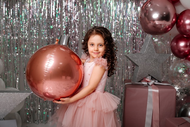 niña en un vestido elegante con globos y confeti